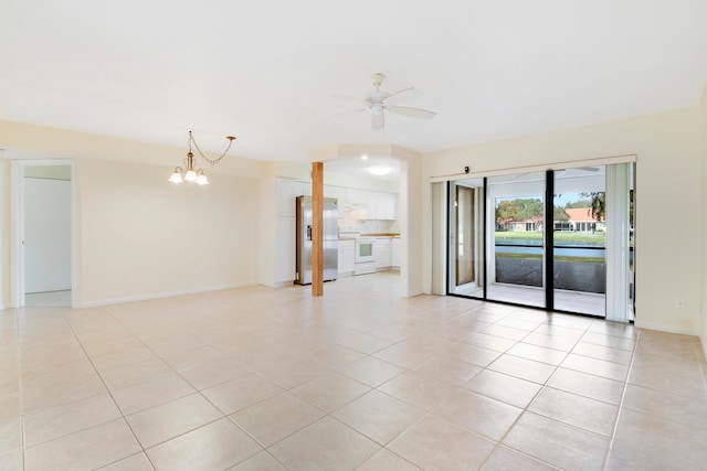 empty room featuring ceiling fan with notable chandelier and light tile patterned flooring