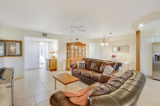 tiled living room with ceiling fan with notable chandelier