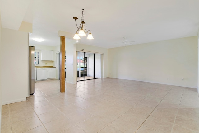 empty room featuring light tile patterned floors and ceiling fan with notable chandelier