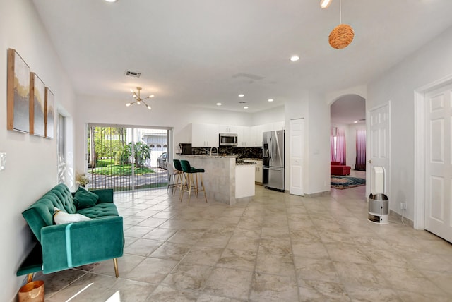 kitchen featuring appliances with stainless steel finishes, tasteful backsplash, white cabinets, light tile patterned flooring, and a breakfast bar