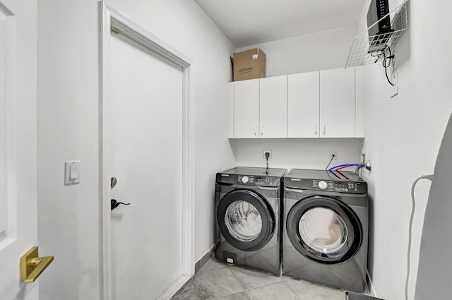 laundry room featuring washing machine and dryer, light tile patterned flooring, and cabinets