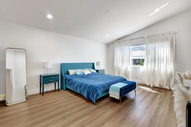 bedroom featuring light wood-type flooring and vaulted ceiling