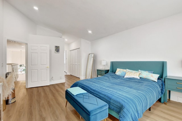 bedroom with light wood-type flooring and lofted ceiling