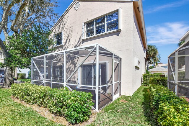 back of property featuring a lanai, a yard, and stucco siding