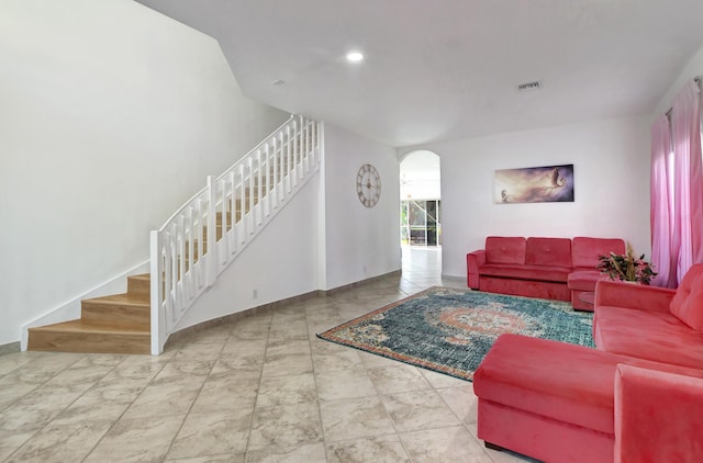 living area with stairs, arched walkways, visible vents, and baseboards