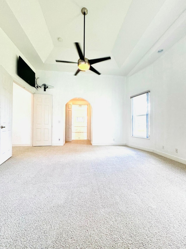 carpeted empty room featuring ceiling fan and a raised ceiling