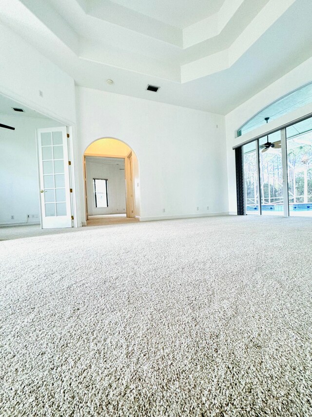 carpeted spare room featuring ceiling fan and a tray ceiling