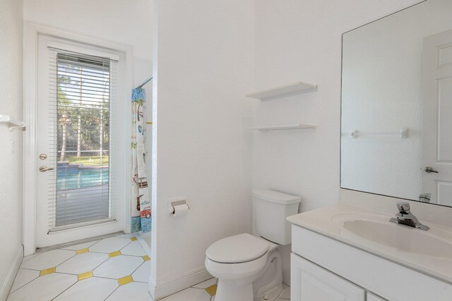 bathroom with toilet, vanity, and tile patterned floors