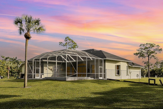 back house at dusk with a lawn and a lanai