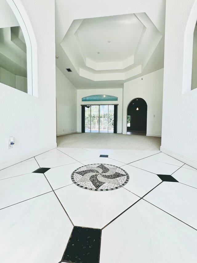 unfurnished living room featuring a tray ceiling and tile patterned floors