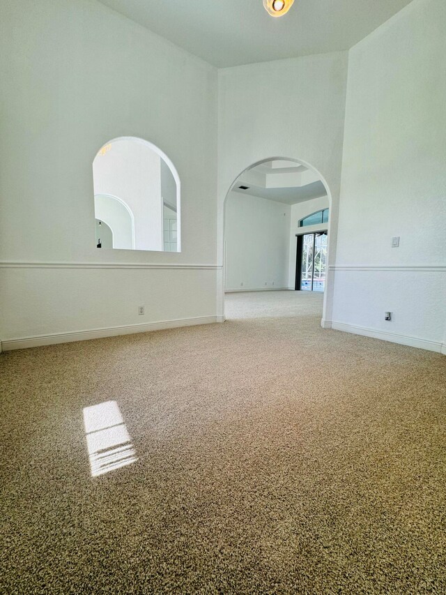 spare room with a towering ceiling and carpet flooring