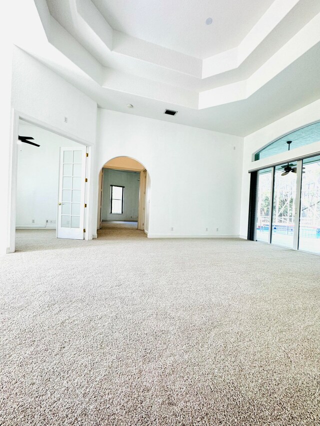 spare room with light colored carpet, ceiling fan, and a raised ceiling