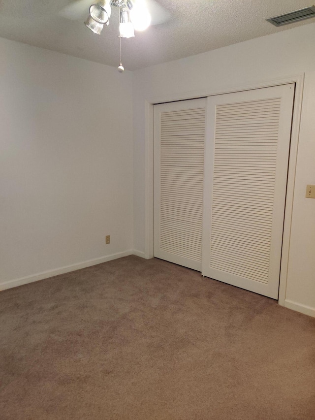 unfurnished bedroom featuring a textured ceiling and light colored carpet