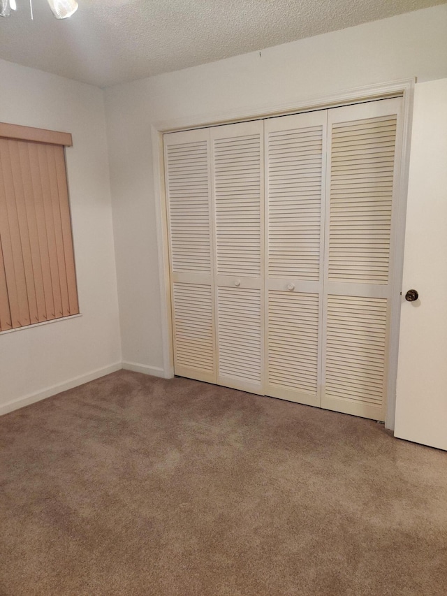 unfurnished bedroom with carpet, a closet, and a textured ceiling