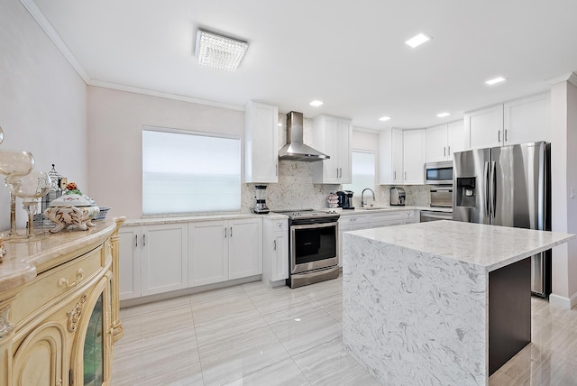 kitchen with stainless steel appliances, white cabinetry, wall chimney exhaust hood, sink, and light stone counters