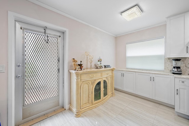 kitchen featuring decorative backsplash, crown molding, white cabinetry, and light tile patterned flooring