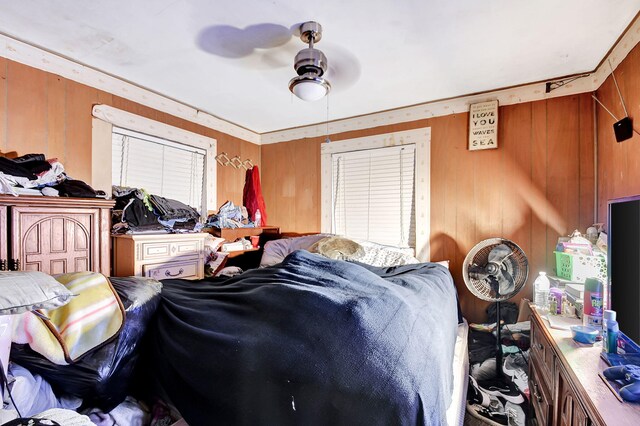 bedroom with ceiling fan and wooden walls