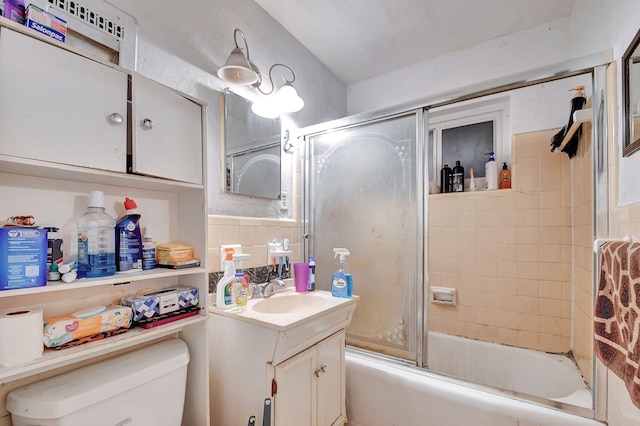 full bathroom featuring combined bath / shower with glass door, vanity, and toilet