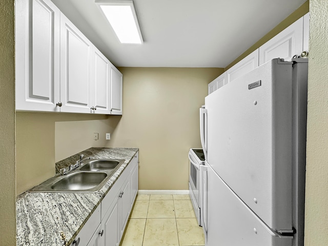 kitchen with sink, light stone countertops, light tile patterned flooring, white cabinetry, and white appliances