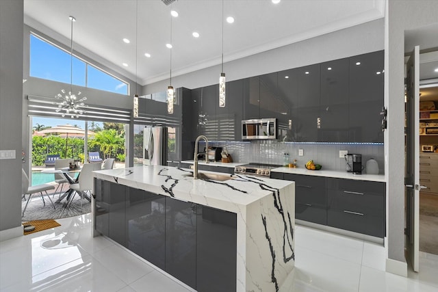 kitchen with decorative backsplash, light tile patterned floors, stainless steel appliances, and a large island with sink