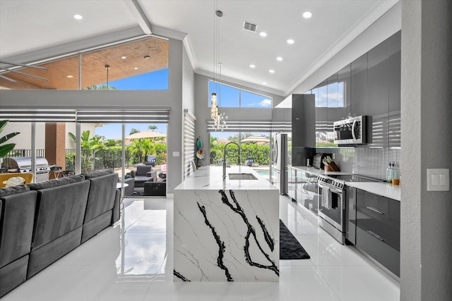 kitchen featuring backsplash, light tile patterned floors, appliances with stainless steel finishes, light stone counters, and high vaulted ceiling