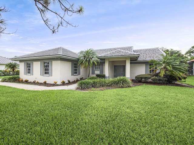 view of front of property featuring a tiled roof, a front lawn, and stucco siding