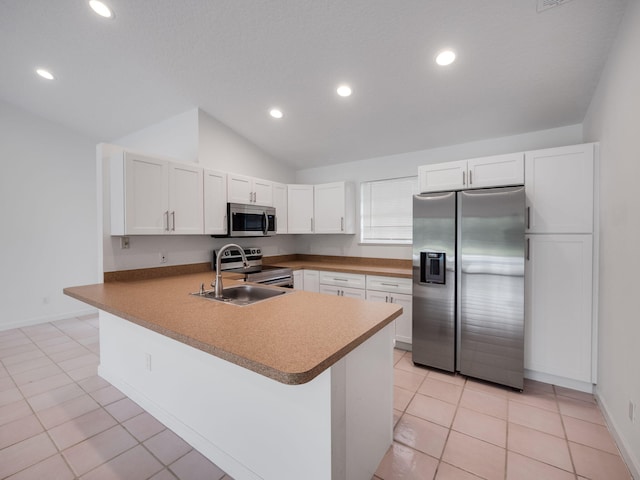 kitchen with appliances with stainless steel finishes, a peninsula, vaulted ceiling, white cabinetry, and a sink