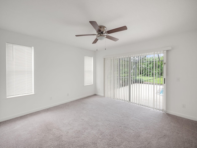 carpeted empty room featuring a ceiling fan and baseboards