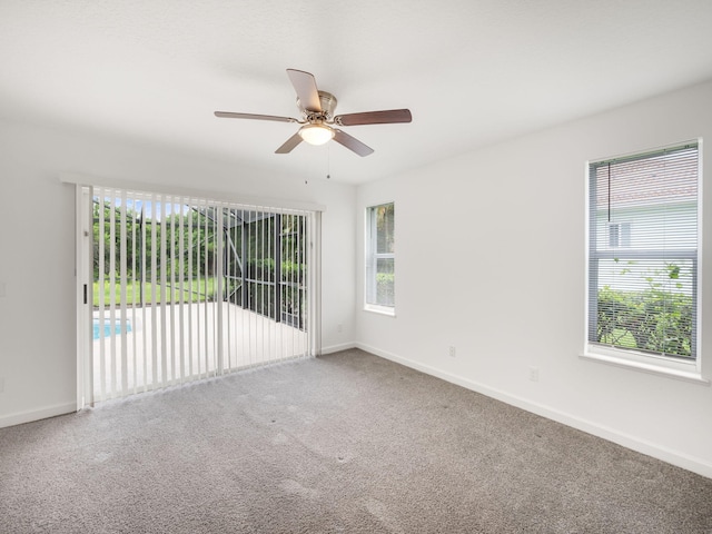 carpeted spare room with a ceiling fan and baseboards