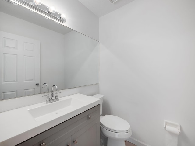 half bathroom with vanity and toilet