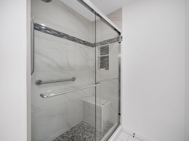 full bathroom with a shower stall and baseboards