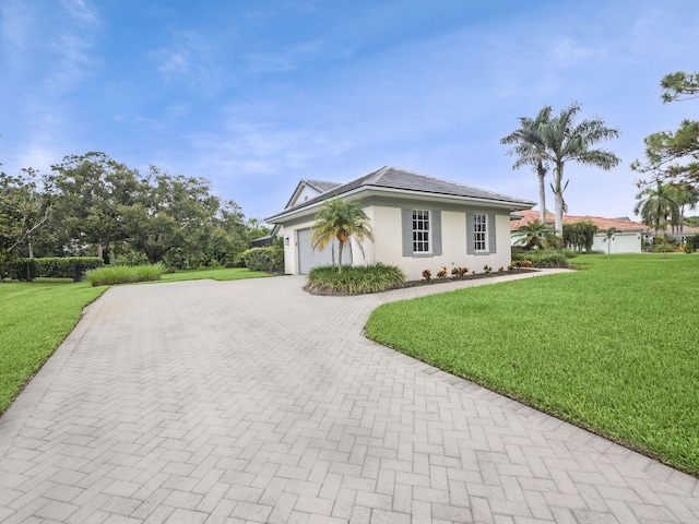 view of front of home featuring decorative driveway, an attached garage, stucco siding, and a front yard