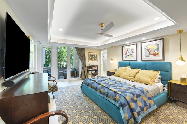 bedroom featuring a tray ceiling, hardwood / wood-style flooring, access to outside, and ceiling fan