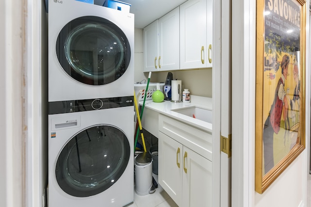 laundry room featuring light tile patterned floors, sink, cabinets, and stacked washer / dryer