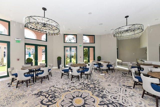 interior space featuring a towering ceiling, french doors, and a notable chandelier