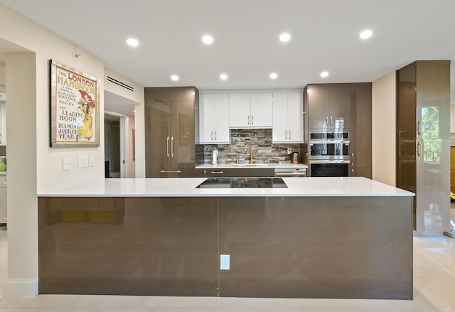 kitchen with tasteful backsplash, stainless steel double oven, sink, black electric cooktop, and white cabinets