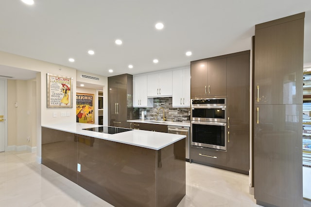 kitchen with backsplash, stainless steel appliances, a kitchen breakfast bar, sink, and white cabinets