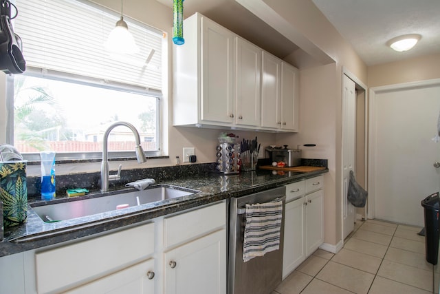 kitchen with hanging light fixtures, white cabinets, light tile patterned floors, sink, and dark stone countertops