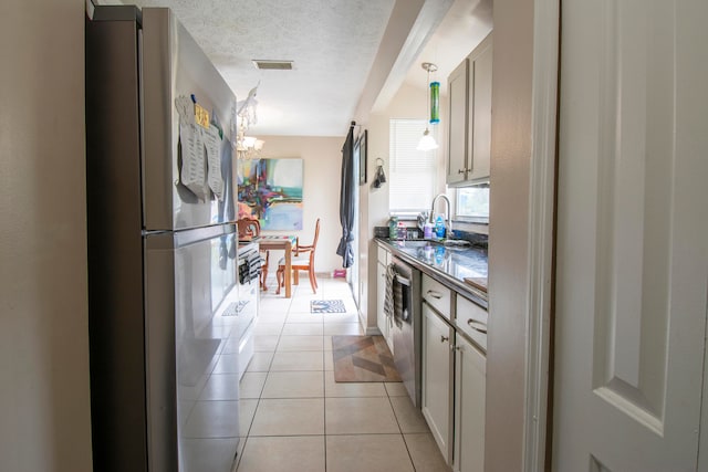 kitchen with stainless steel appliances, sink, a textured ceiling, light tile patterned flooring, and hanging light fixtures