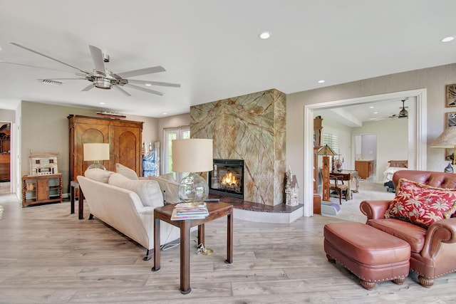 living room featuring ceiling fan, light hardwood / wood-style floors, and a premium fireplace