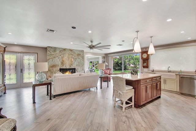 kitchen featuring a fireplace, dishwasher, light hardwood / wood-style floors, and a center island