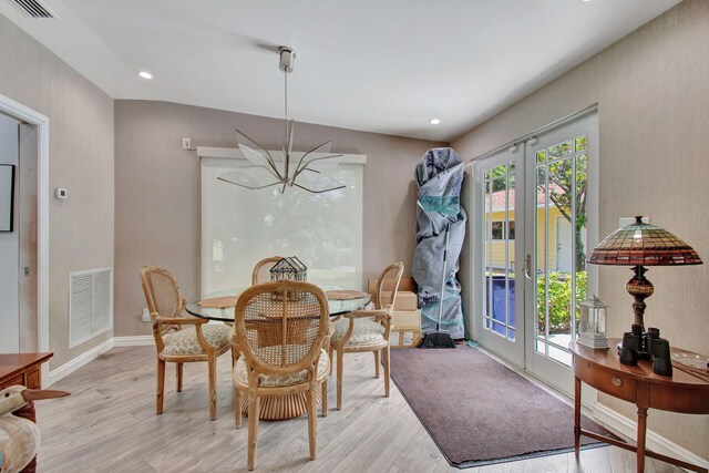 dining room with plenty of natural light, light hardwood / wood-style flooring, french doors, and a chandelier