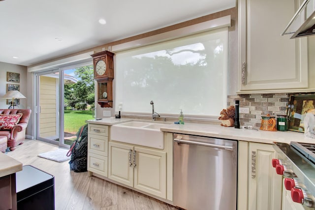 kitchen with sink, light wood-type flooring, stainless steel dishwasher, tasteful backsplash, and cream cabinetry