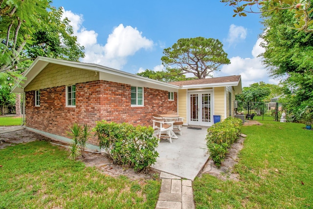 view of front of home featuring a patio, central air condition unit, a front lawn, and french doors