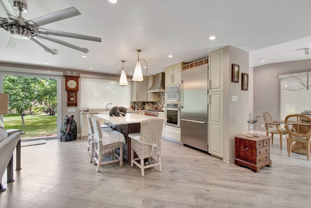 kitchen with ceiling fan, light wood-type flooring, hanging light fixtures, appliances with stainless steel finishes, and cream cabinetry