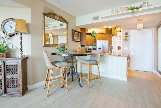 kitchen featuring built in fridge, visible vents, brown cabinets, and a peninsula