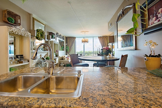 kitchen featuring dark countertops, a notable chandelier, a textured ceiling, and a sink