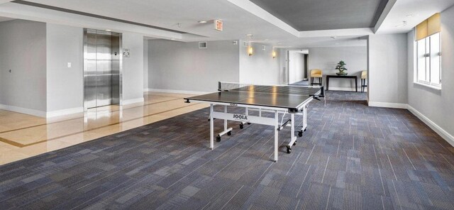 playroom featuring elevator, baseboards, and a raised ceiling