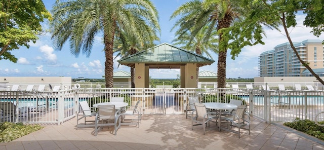 view of patio with a gazebo, fence, and a community pool