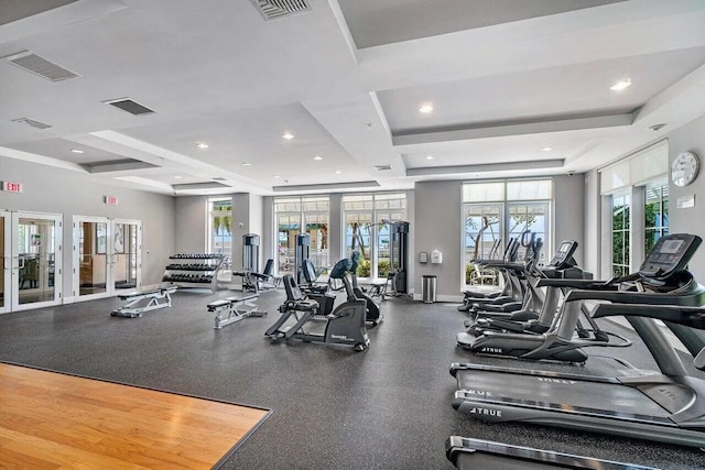 gym featuring recessed lighting, visible vents, a raised ceiling, and french doors